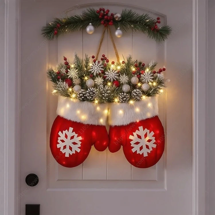 Décoration Noël gants rouges accrochée à une porte, remplie de branches de sapin, baies rouges, flocons blancs, pommes de pin et guirlande lumineuse LED.”