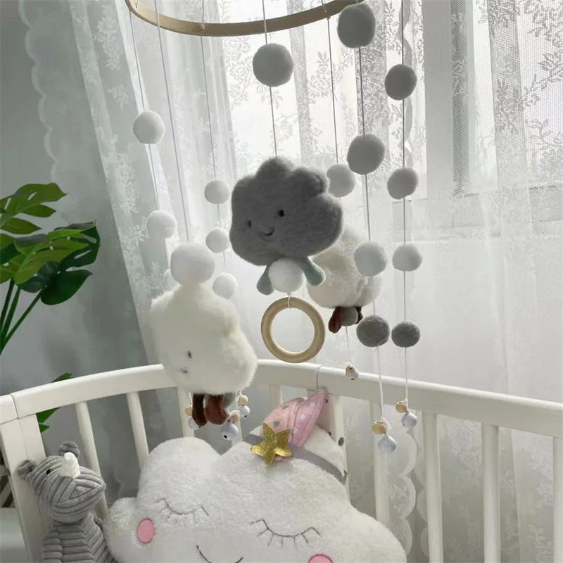 Lit de bébé décoré par un mobile en nuage gris et blanc