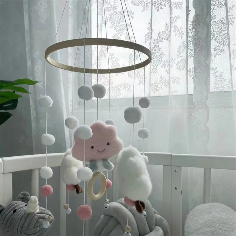 Mobile en nuage rose et blanc installé dans le lit de bébé