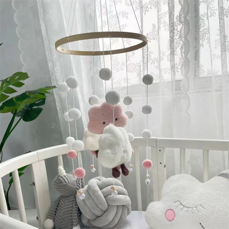 Mobile en nuage rose et blanc installé sur le lit de bébé 