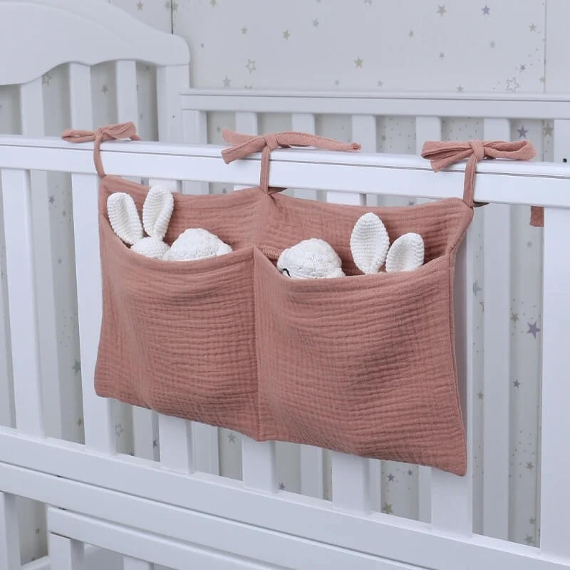 Pochette de lit bébé rose pastel suspendue sur le côté d’un berceau moderne