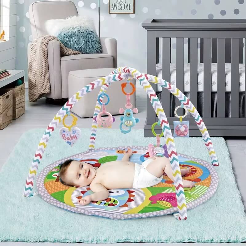 Bébé jouant sur le tapis d'éveil Dreamy Play™ avec arche multicolore et jouets suspendus.