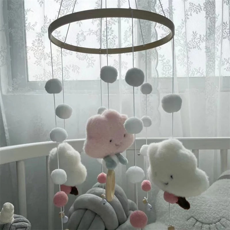 Lit de bébé avec un mobile en nuage rose et blanc