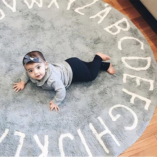 Tapis chambre bébé Alphabet Ring déployé au sol avec toutes les lettres de l’alphabet visibles, dans une chambre d’enfant lumineuse.